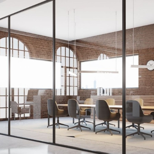 Contemporary meeting room with glass walls, arched brick windows, modern chairs, and ample natural light creating an elegant and functional workspace.